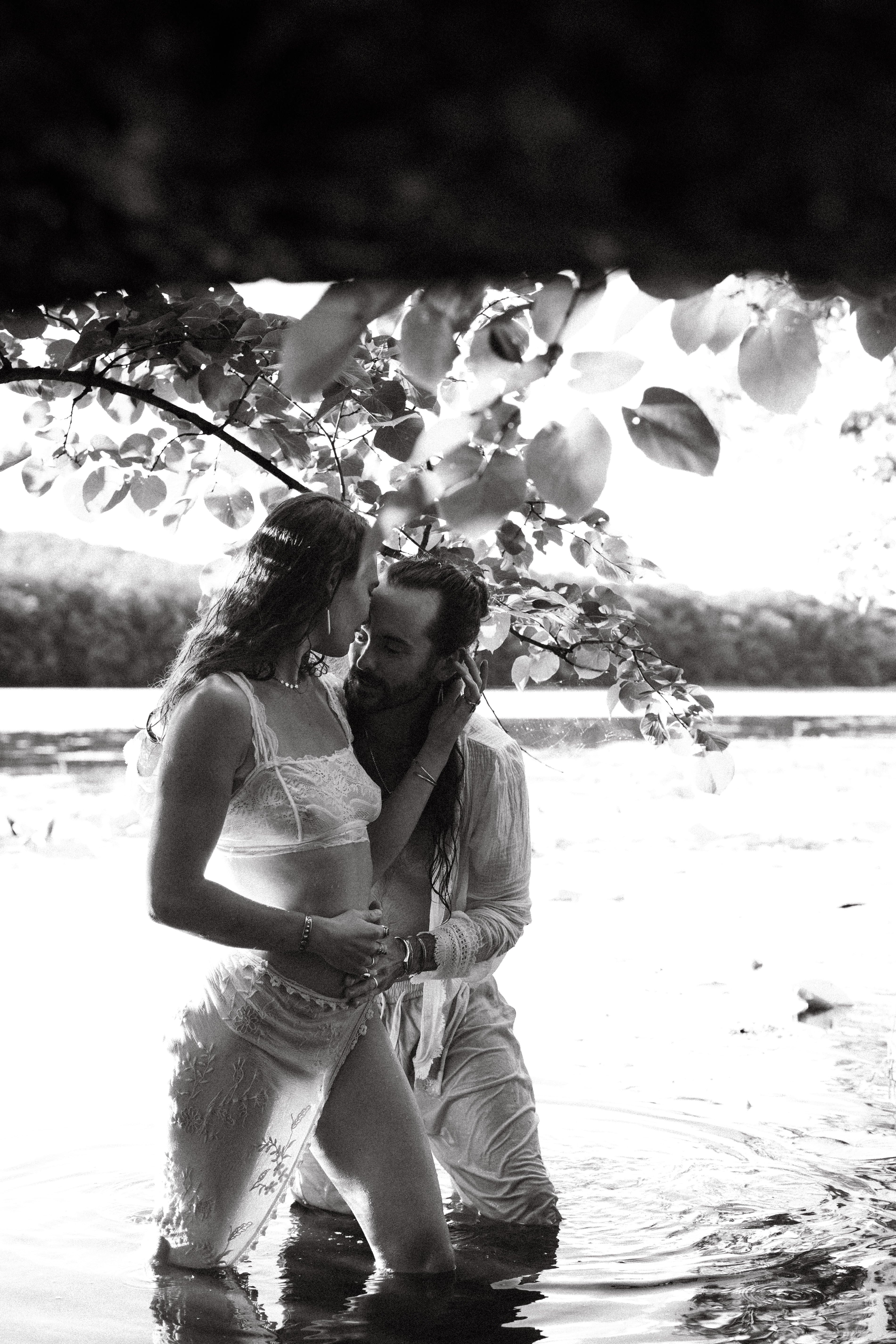 Romantic couple posing together in water with natural surroundings